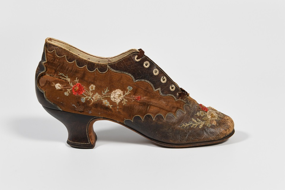 Women's brown leather and silk lace shoe, about 1890s. Found by the donor hidden in the chimney breast of an old manor house in Priors Hardwick, Warwickshire. They feel that the other shoe was also there but they couldn't reach it.