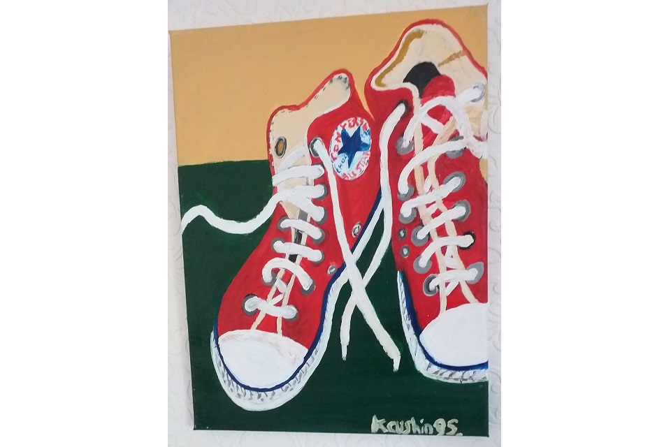 picture showing a pair of red converse all star high top trainers against a background with dark green in lower two thirds and yellow in upper third