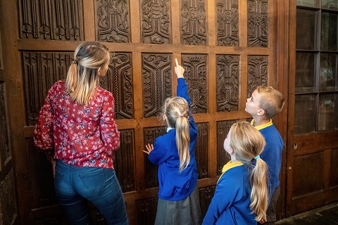 Teacher and three children looking at oak paneling.
