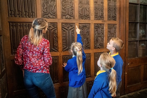 Teacher and three children looking at oak paneling.