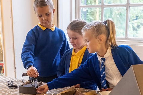 Three children handling museum objects.