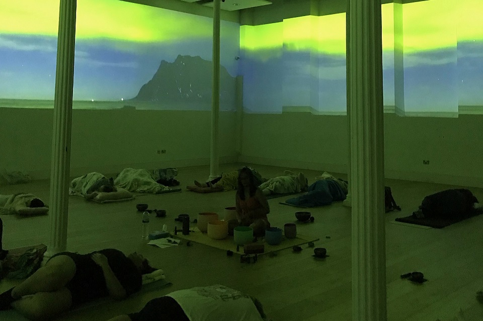 Muted room with yellow and green colours on the walls. Columns with people laying on floor.