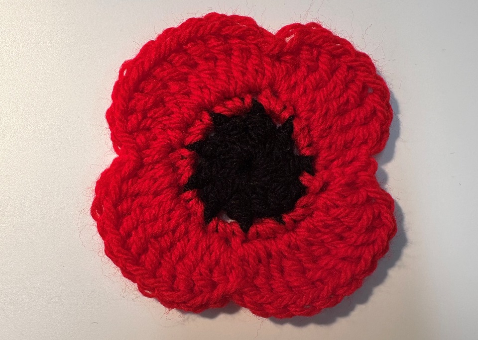 Crocheted poppy with four petals in red with a black centre
