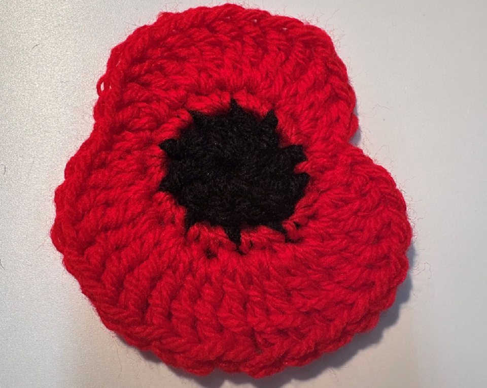 Crocheted poppy with two petals, in red with a black circle centre
