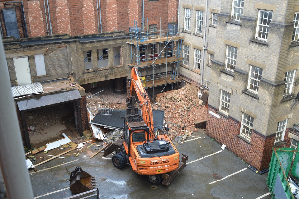 Looking down onto a courtyard area with large orange construction vehicle in the centre.