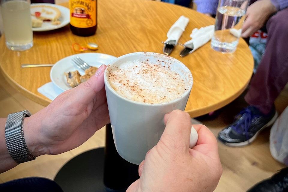 Colour photograph of a pair of hands holding a mug over a table