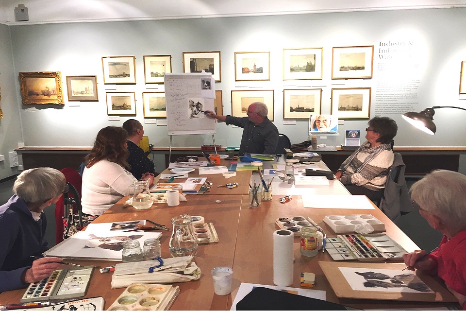 Group of adults with a tutor in a watercolour painting workshop.