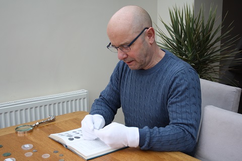 Adult male looking at selection of old coins.