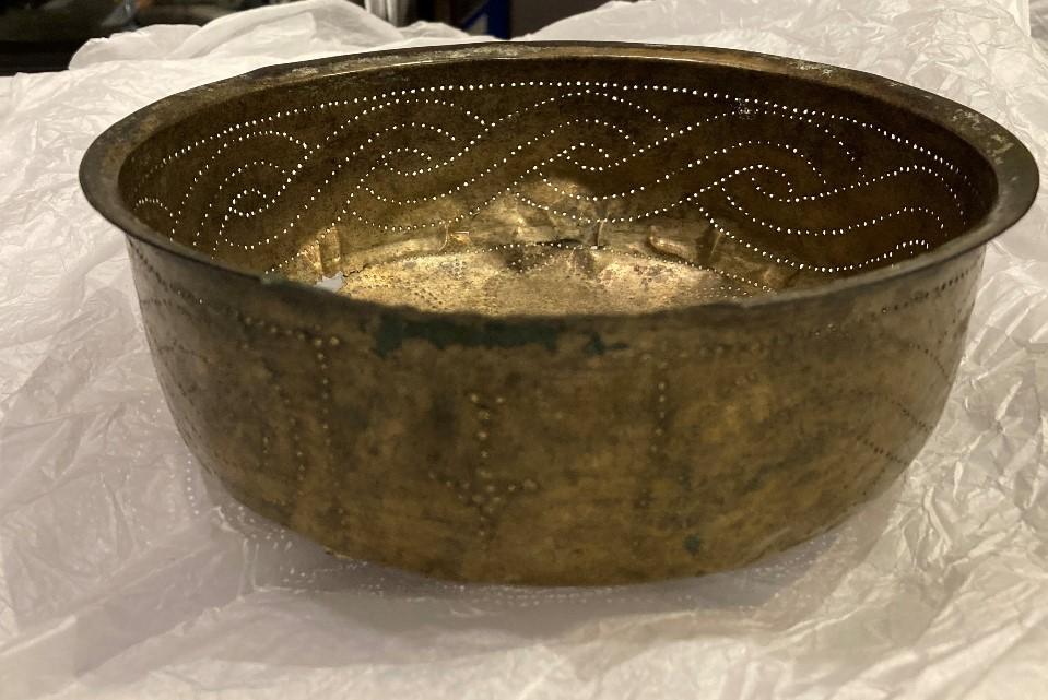 Photograph of bronze shiny bowl. Sides of the bowl are decorated with dotted pattern