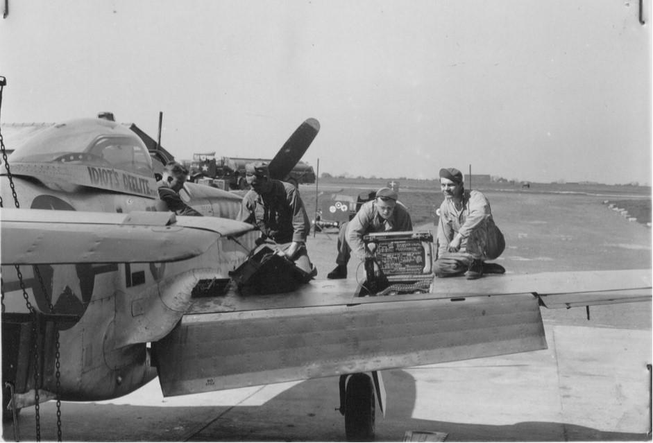 Black and white photograph of two airmen sitting on a plane wing.