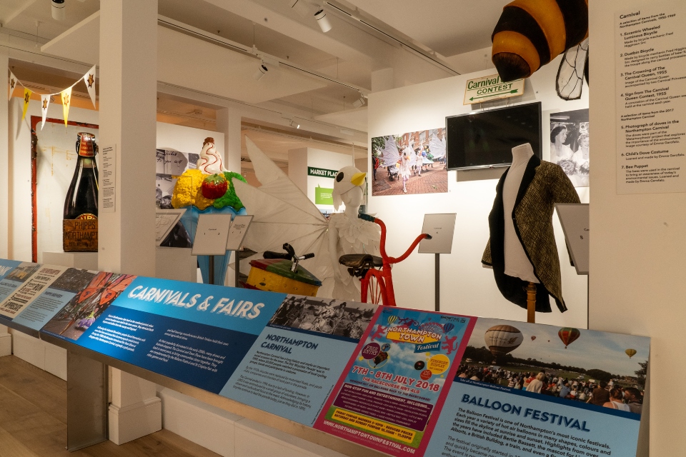 Angled label panels form the foreground of the image, with a waistcoat, bee costume and other large objects behind