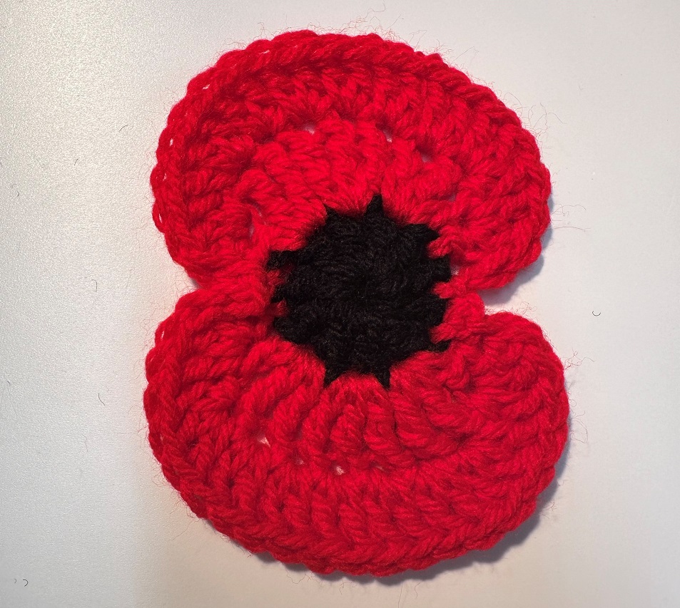 Red crocheted poppy with two petals and a black centre