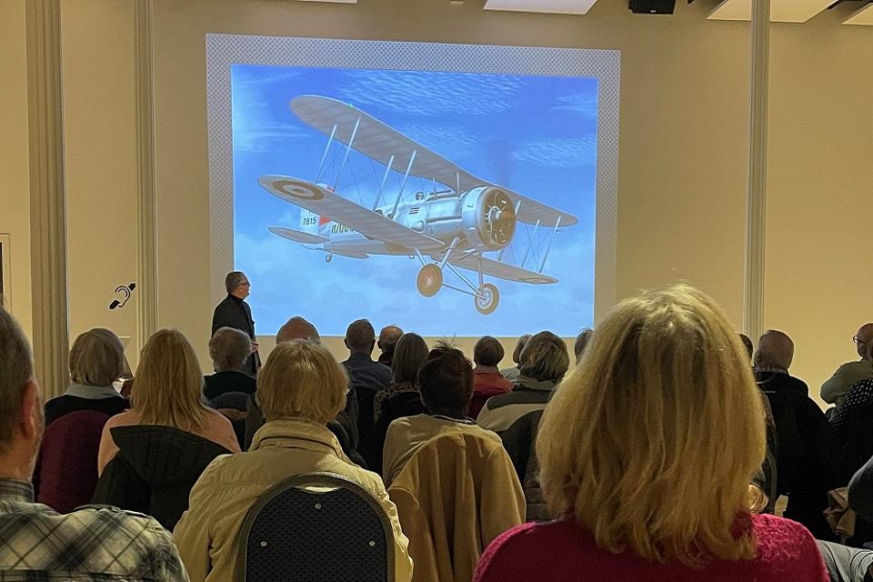 Image of heads from behind looking at an image of areoplanes on the screen