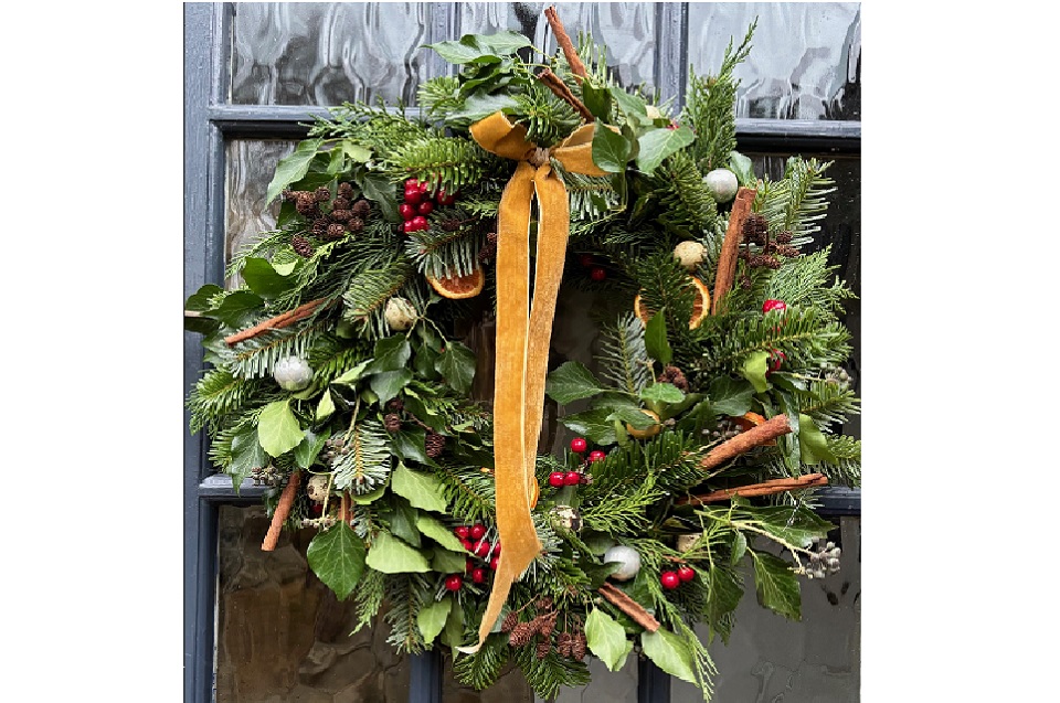 a christmas wreath with lush green foliage, pine cones, and ribbon