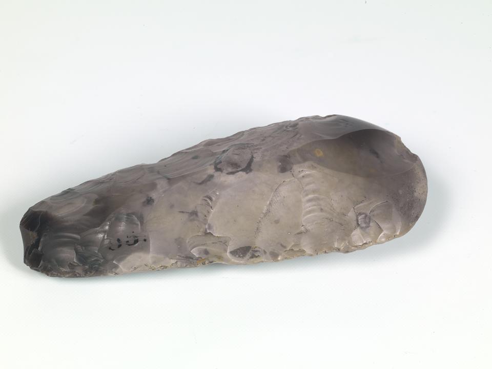 Grey shaped stone object. Narrow end towatds camera splaying out into a wedge.