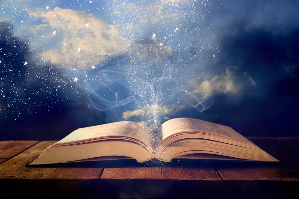 A book open on a table wth light and sparkles coming from the pages.