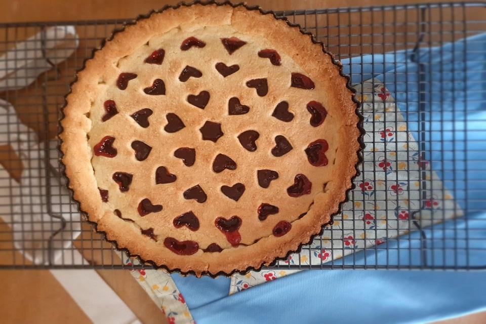 Round shaped golden tart on a cross wire cooling rack with blue cloth behind.