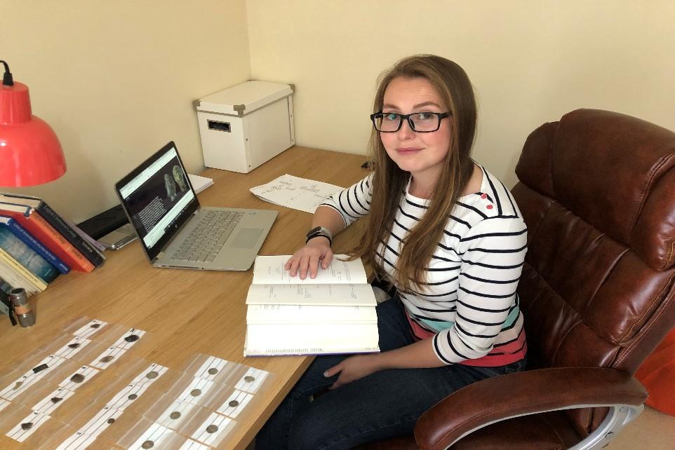 Woman sitting at a desk with bags on table.