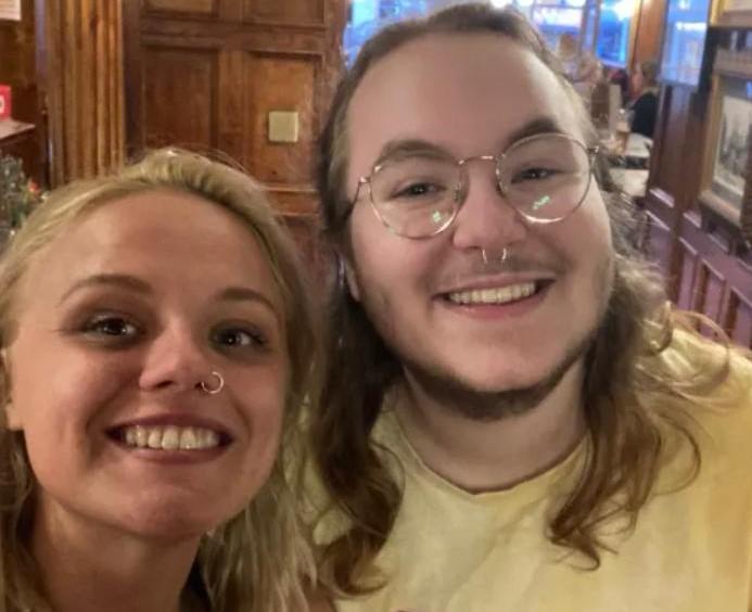 Two young people with piercings smiling into the camera