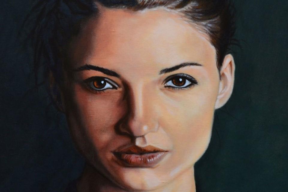 Pale female face looking out of a dark background. Oil painting