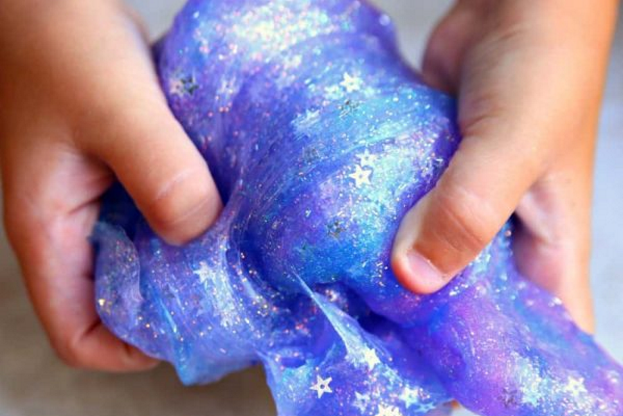 A pair of hands with red painted nails holding a purple and blue mottled fabric