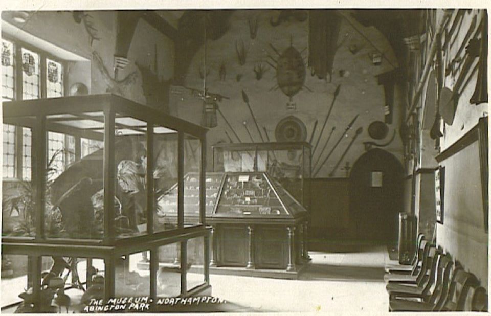 High walled building displaying spears, shields on the wall and two large cases in the foreground.