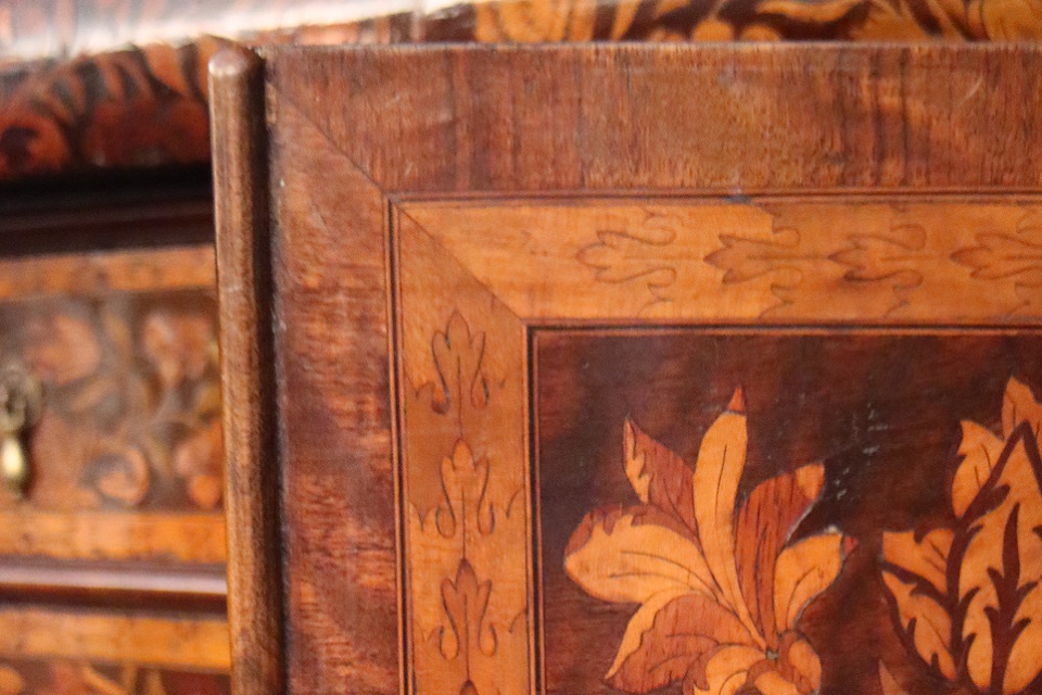 Wood door partially open with decorative patterned wood depicting flowers and folliage.