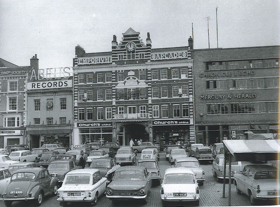 Black and White image of the Emporium Arcade, with cars parked in front on the Market Square