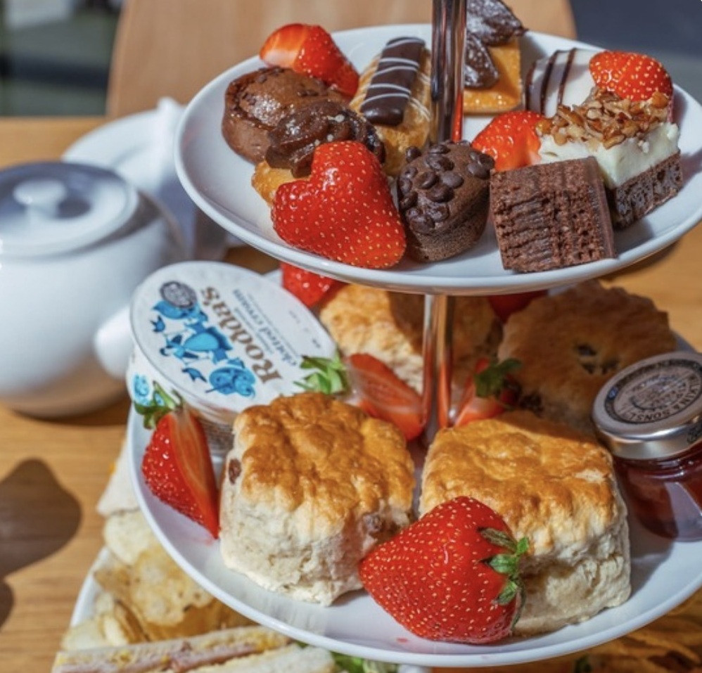 Afternoon tea two tiered cake plate with scones, strawberries and mini chocolage cakes