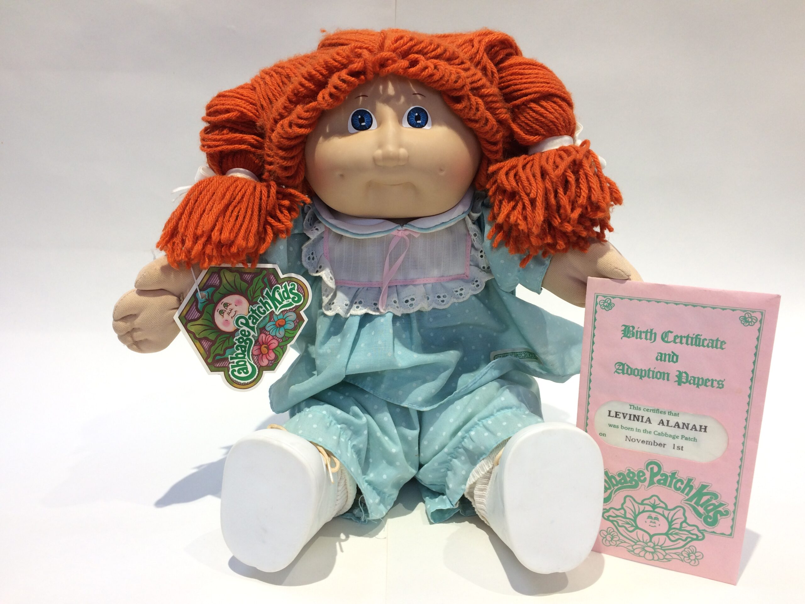 Cabbage Patch Kids Cabbage Patch Kids doll with bright orange yarn hair in pigtails, wearing a teal dress, holding a tag and displayed with adoption papers.